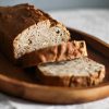 Close-up of rustic homemade bread loaf with slices on a wooden platter.